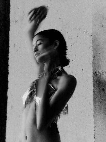 Zendaya in black and white portrait with arms raised.