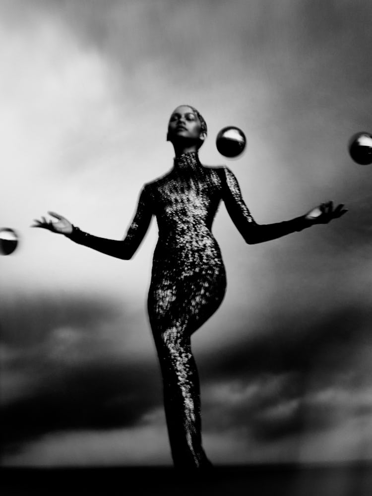 Zendaya juggling silver orbs in black and white.