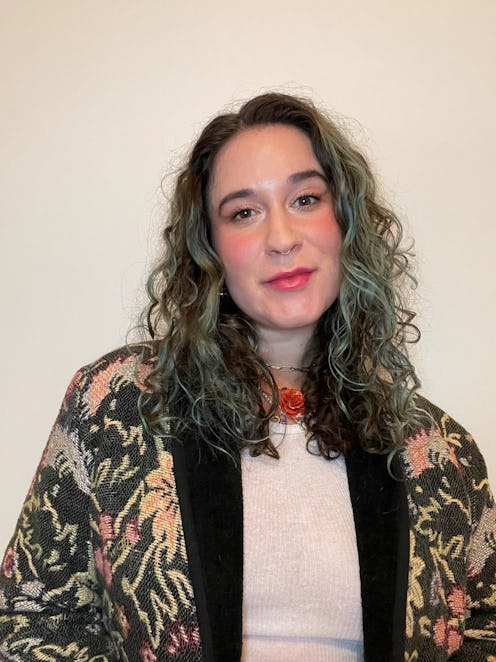Woman with teal and brown curly hair and flushed pink makeup
