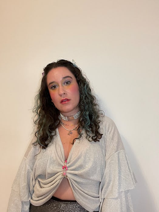 Woman with teal curly hair pinned back in the front with butterfly clips and rainbow eye makeup 