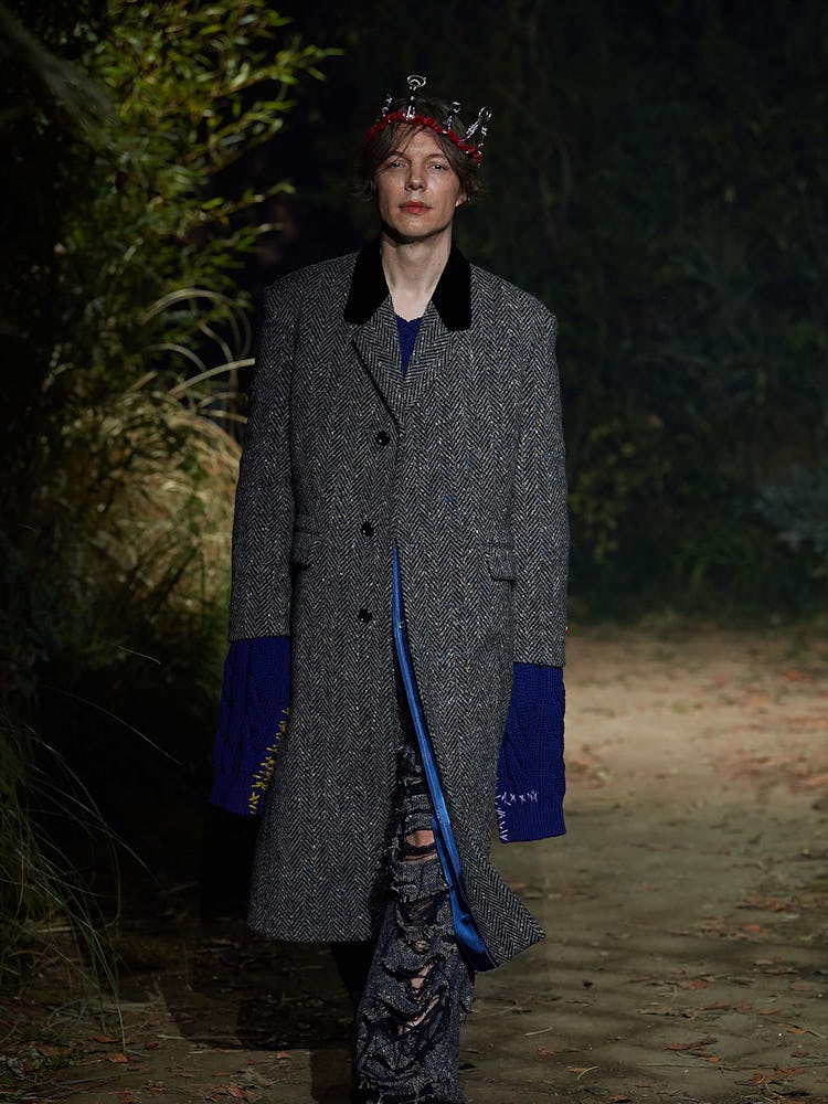 A model in a long grey jacket with blue sleeves walking the Marni fall 2022 Milan fashion week runwa...