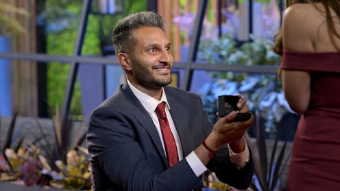 Shake from 'Love Is Blind' in a suit and on one knee proposing with an engagement ring in his hand.