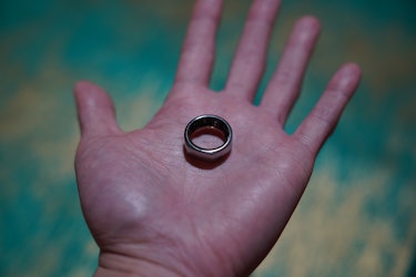 The silver version of the Oura Ring in an open palm 