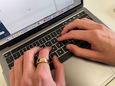 Wearing the gold Oura Ring while typing on a MacBook Pro 