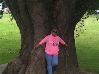 Woman standing against large tree trunk