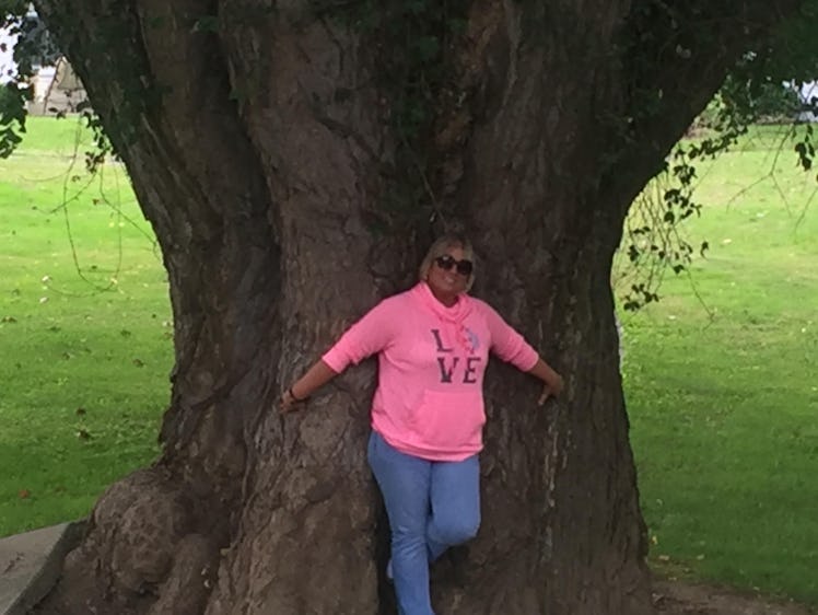 Woman standing against large tree trunk