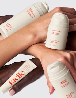 Two hands holding four Facile Skin brand skin care products