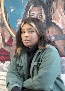 Qualeasha Wood portrait in front of her tapestry artwork