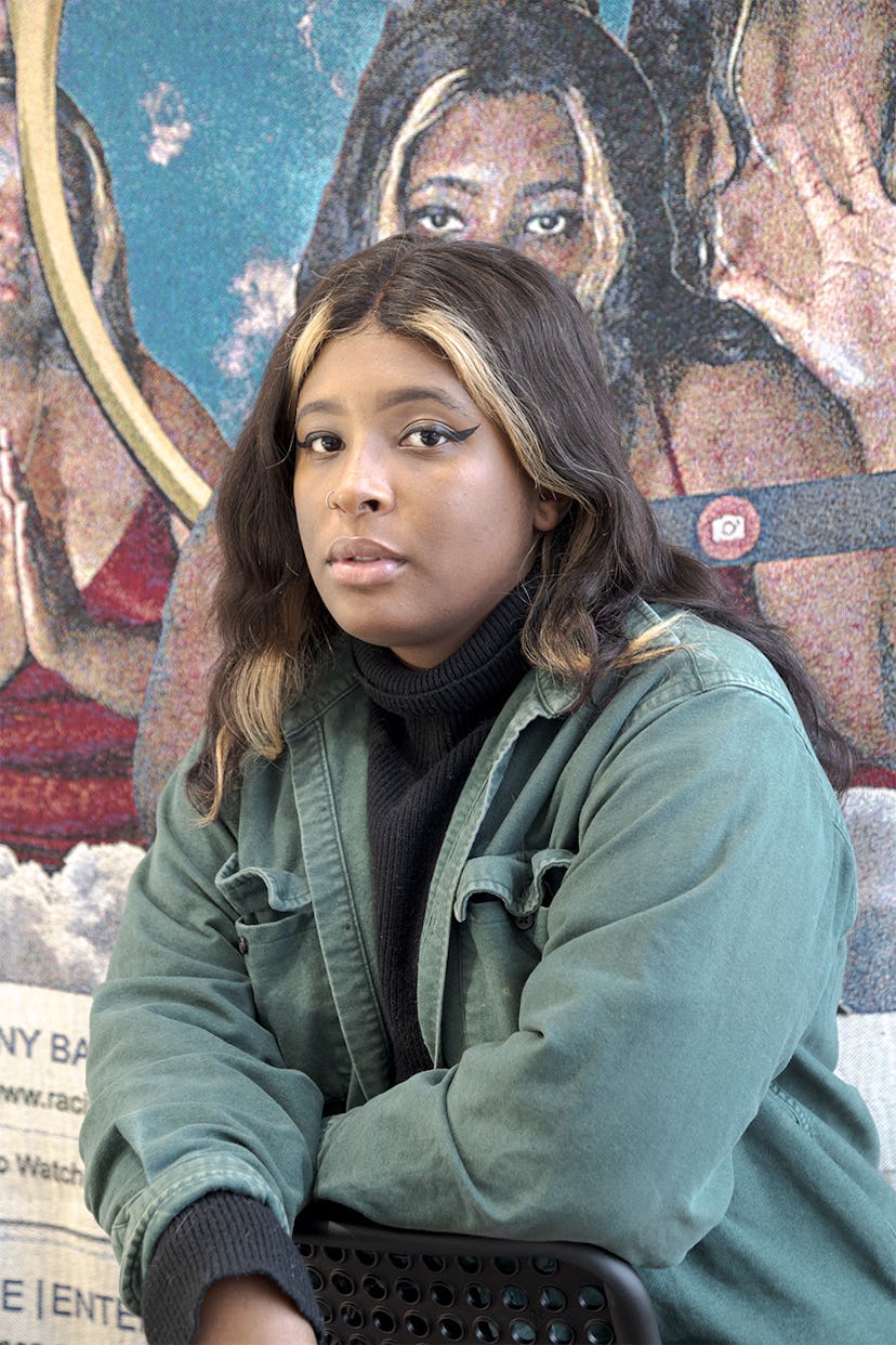 Qualeasha Wood portrait in front of her tapestry artwork