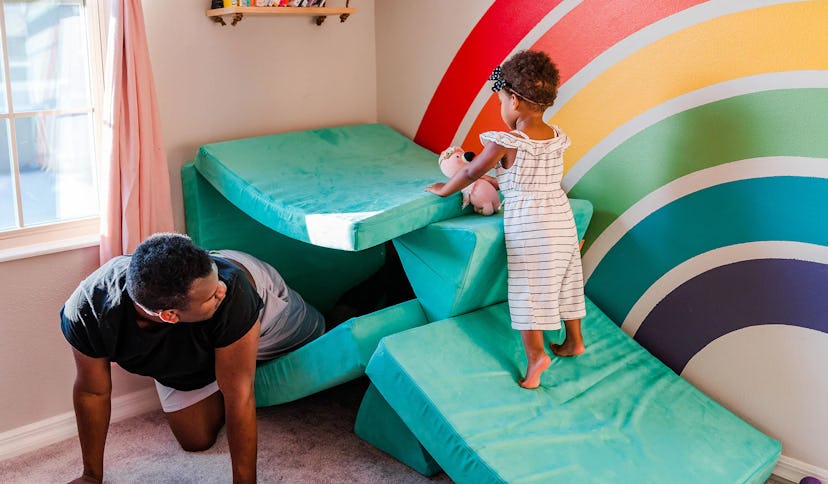 child and dad playing with teal nugget couch