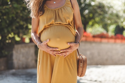 woman in sundress holding her pregnant belly