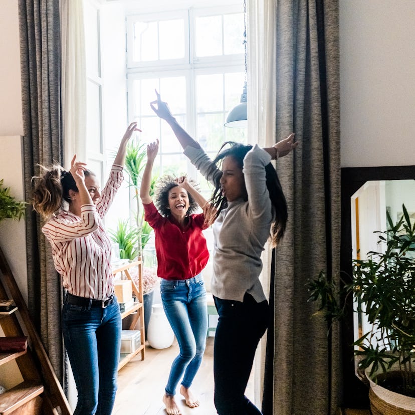 Three young women jumping up and down at home as their zodiac signs celebrate Galentine's Day 2022.