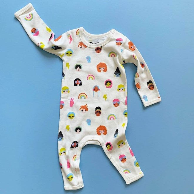 Flat lay of baby long-sleeve romper with cartoon faces and doodles