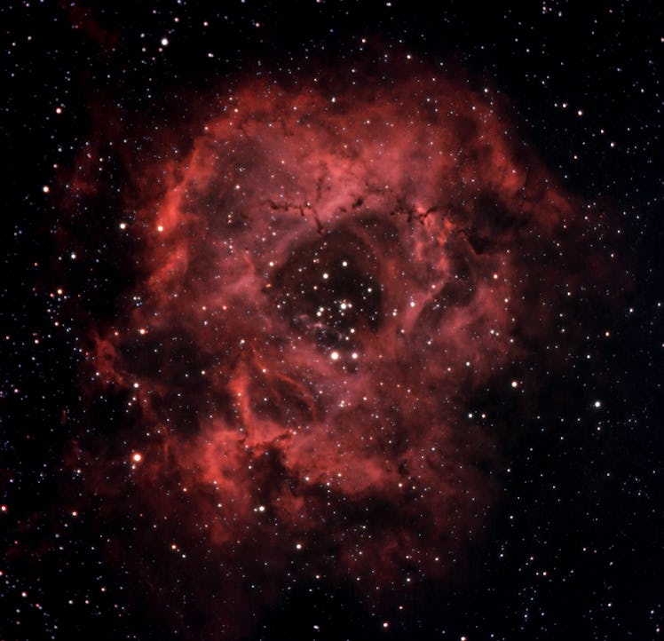 Deep space image of the Rosetta Nebula, with its gas marked by an illuminated red color surrounded b...