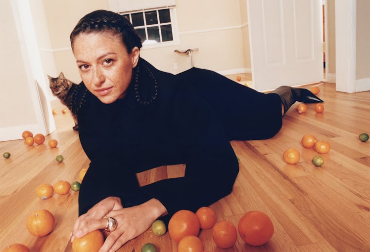 A model lying on the floor in a black dresses by Khiry with oranges around her