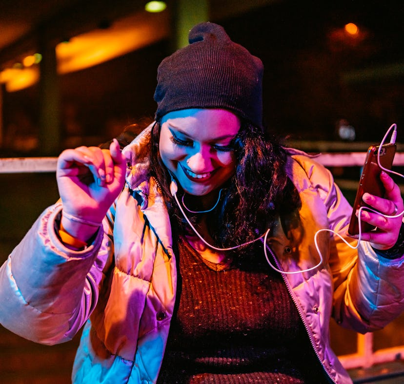 Young woman listening to music on her phone, having the best week of February 14, 2022, per her luck...