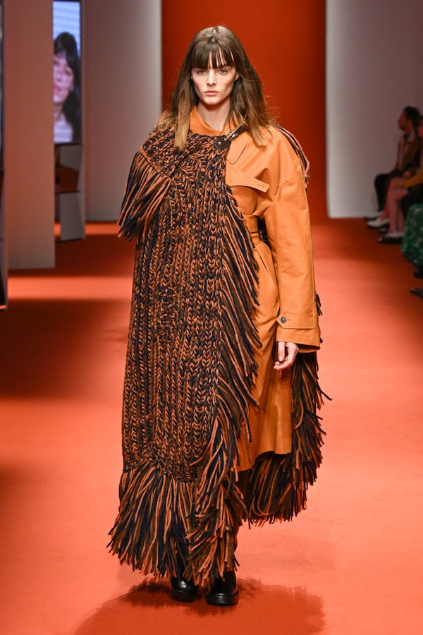a model wearing a knitted fringe cape on the Tod's runway