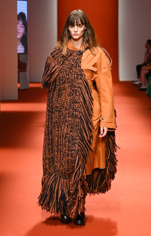 a model wearing a knitted fringe cape on the Tod's runway