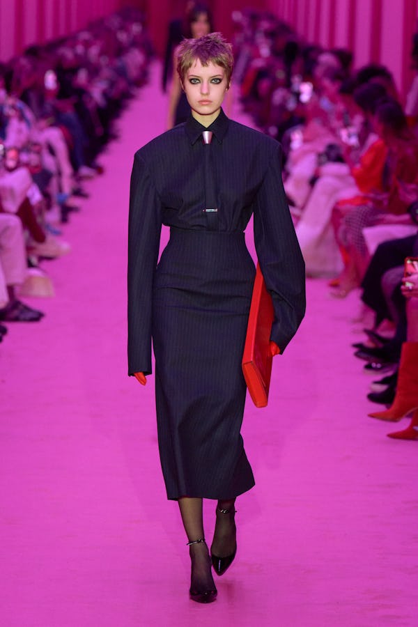 A model wearing a tailored pinstripe shirt and pencil skirt on the Sportmax Runway