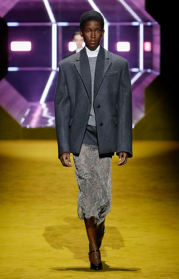 A model wearing a grey blazer and sheer silver skirt on the Prada runway
