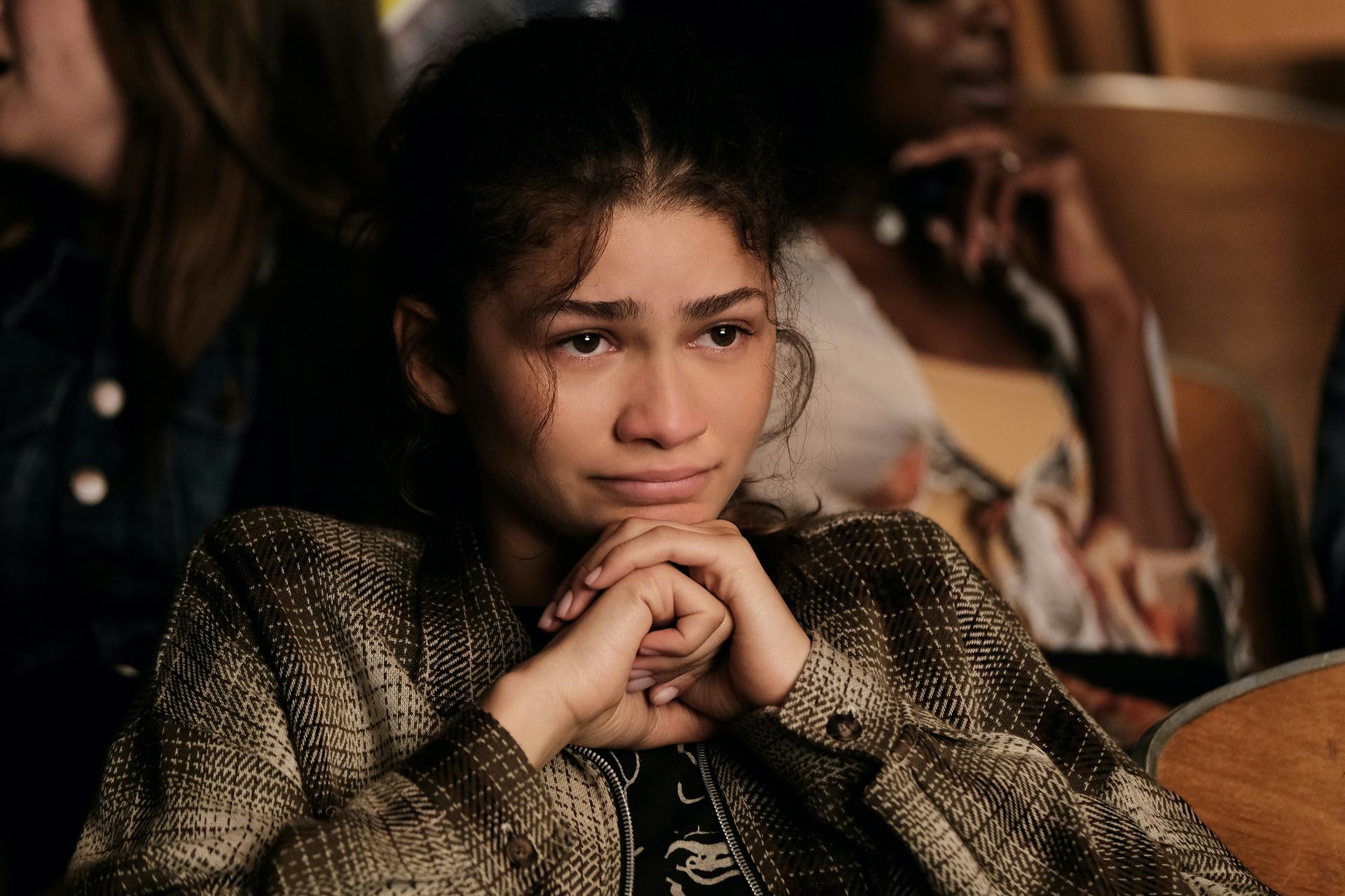 Zendaya, from "Euphoria", sitting down with hands under her chin, looking like she is close to tears...