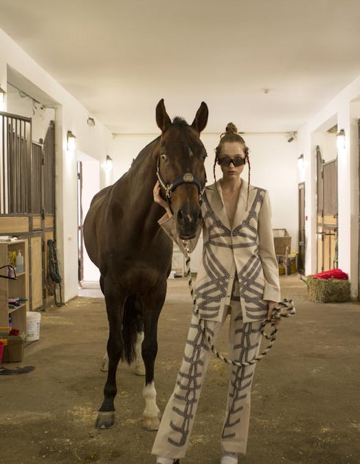 A model wearing Jean Gritsfeldt standing next to a horse