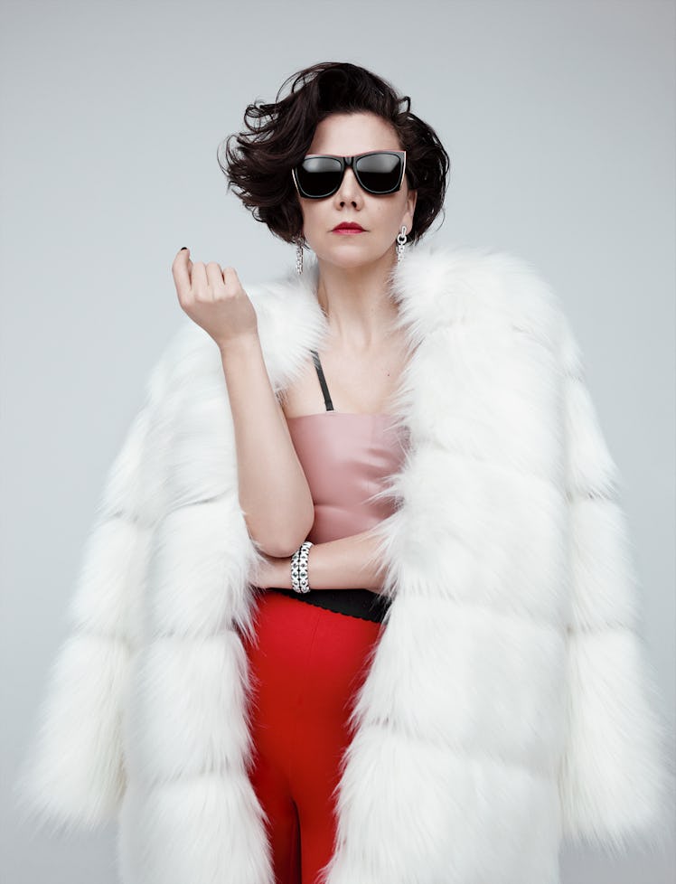 Maggie Gyllenhaal in a pink top, white furry coat and red leggings