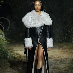 a model wearing a black leather coat with white trim on the Marni runway