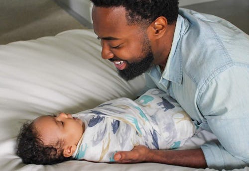 Father smiling at his baby wrapped in the best muslin blanket for babies