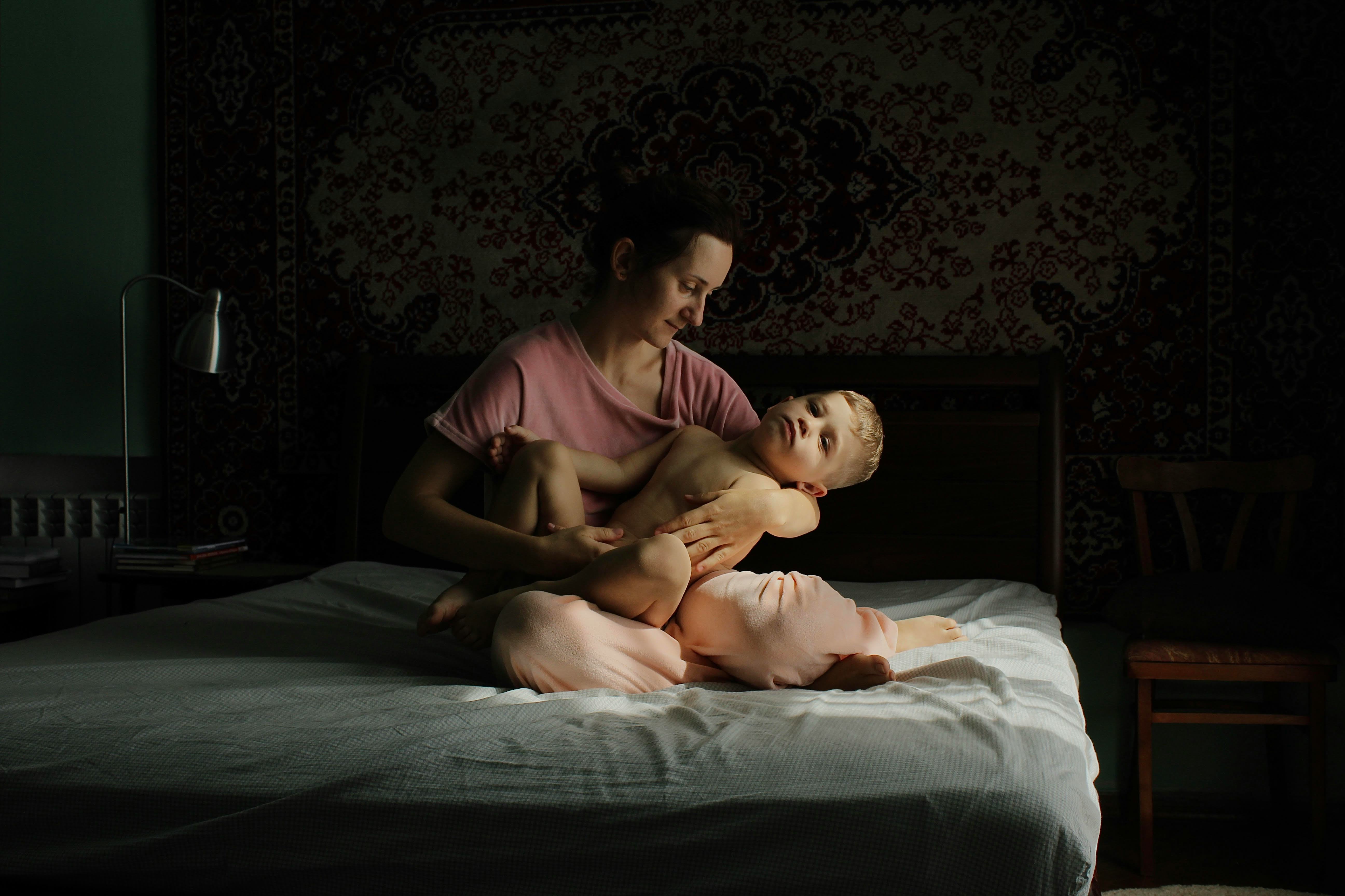 A mother cradles her toddler on a bed