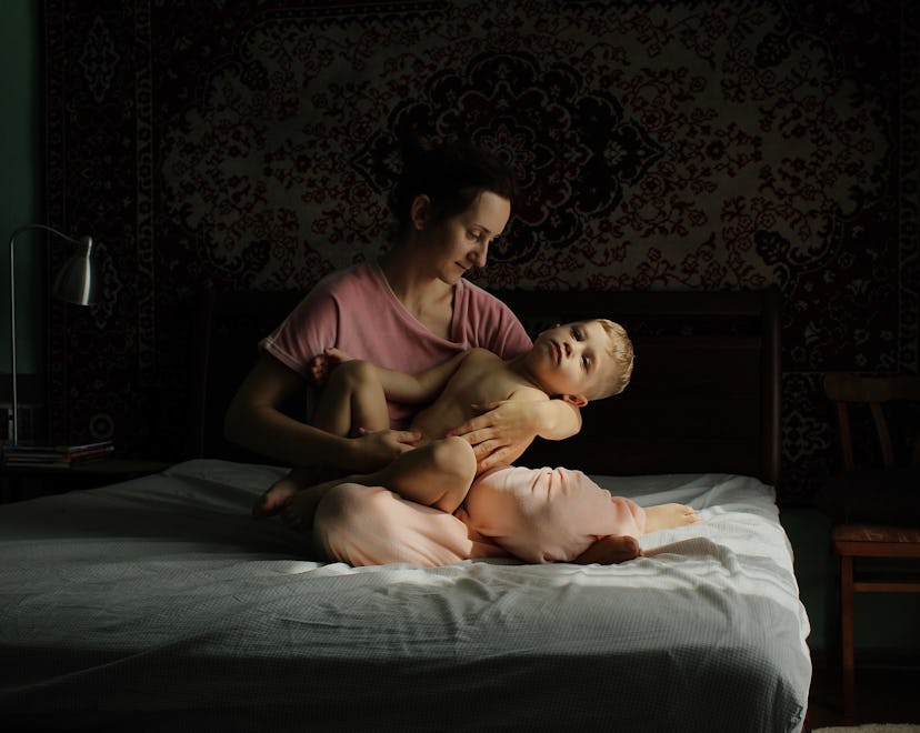 A mother cradles her toddler on a bed