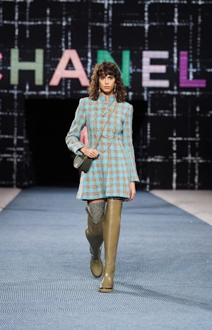 a model wearing green over-the-knee rain boots on the Chanel runway