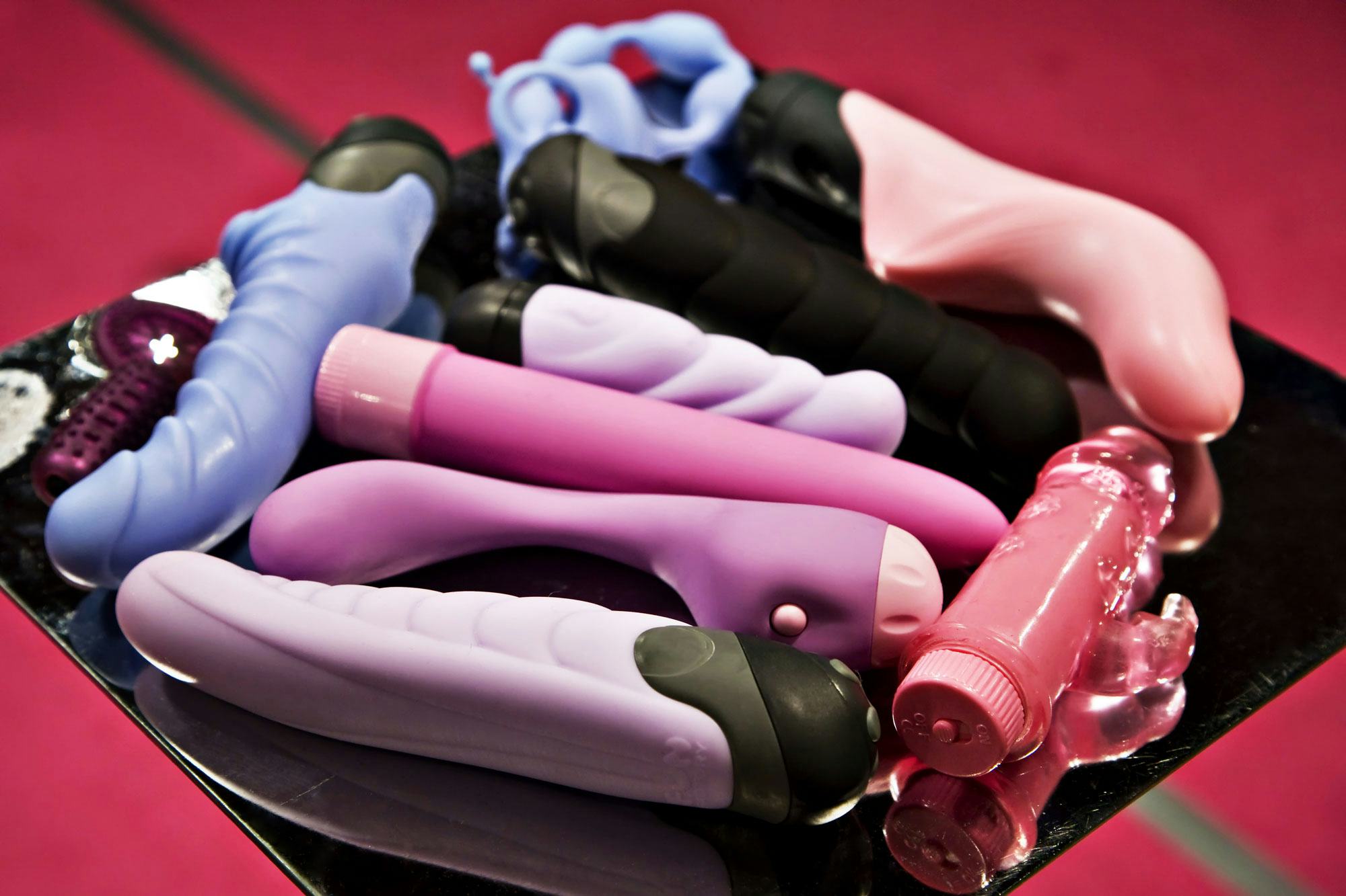 A bunch of vintage vibrators on a black table. Here's a history of the vibrator you never learned in...