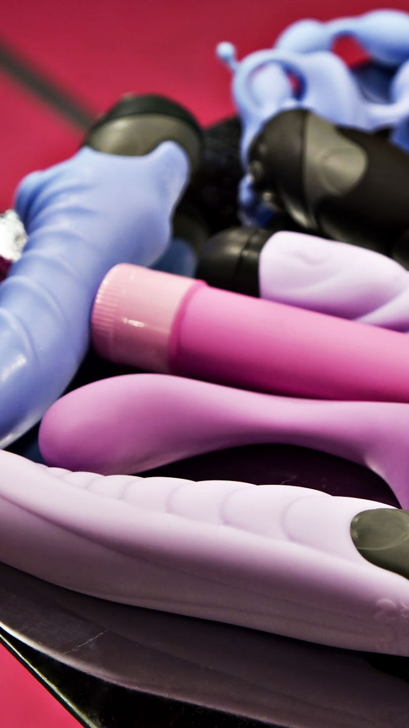 A bunch of vintage vibrators on a black table. Here's a history of the vibrator you never learned in...