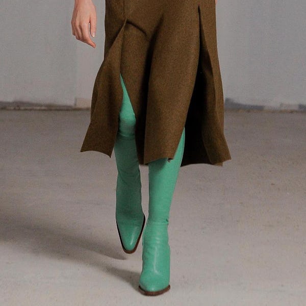 a model wearing green over-the-knee leather boots by Victoria Beckham