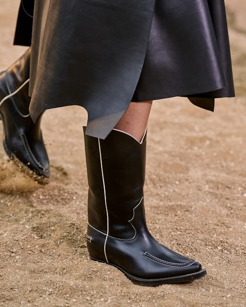 a model wearing black western-inspired cowboy boots on the Chloé runway