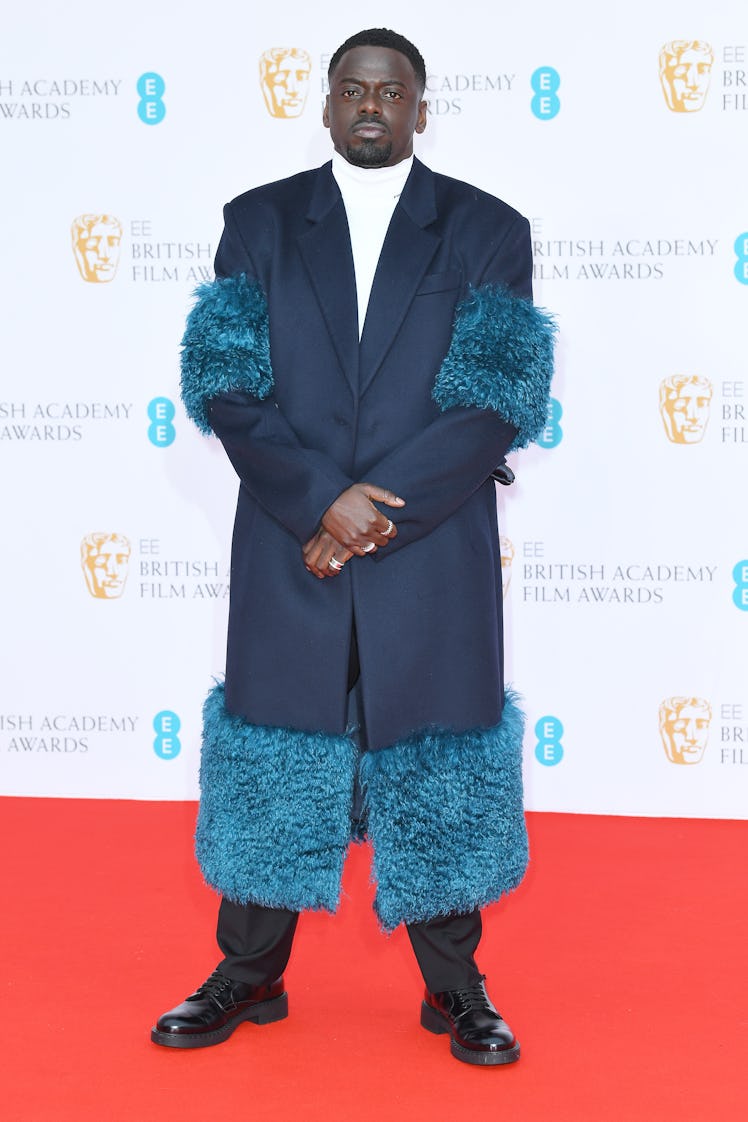 Daniel Kaluuya attends the BAFTA Awards 2022 in a blue coat with fur trim
