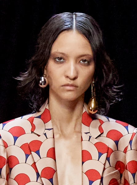 a model wearing a sculptural earring set in yellow gold and silver on the Lanvin runway
