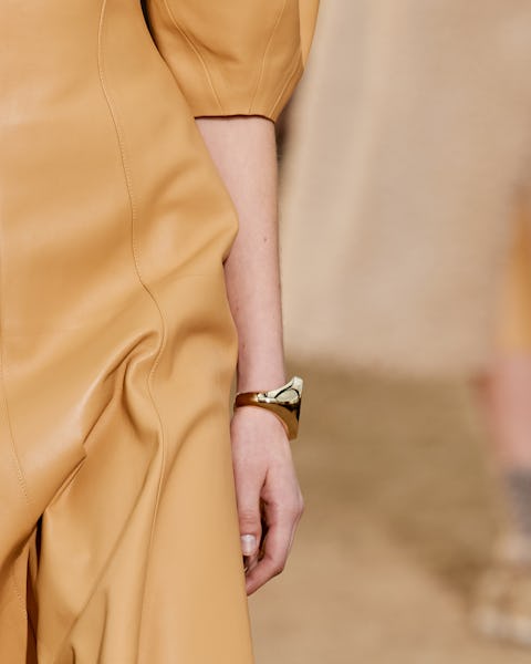 a model wearing a thick yellow gold bangle bracelet on the Chloé runway