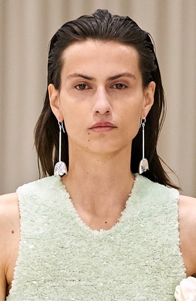 a model wearing silver sculptural floral earrings on the Jil Sander runway
