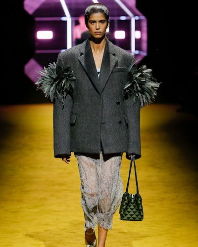 a model wearing a grey blazer and sheer beaded skirt on the Prada runway