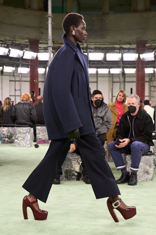 a model wearing an oversize navy coat and suit on the Bottega Veneta runway