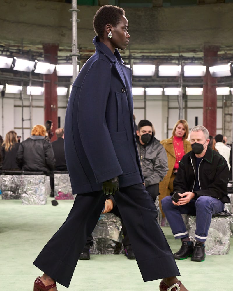 a model wearing an oversize navy coat and suit on the Bottega Veneta runway