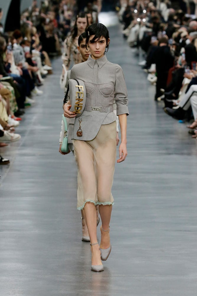 a model wearing a grey shirt and sheer skirt on the Fendi runway