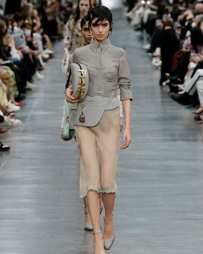 a model wearing a grey shirt and sheer skirt on the Fendi runway