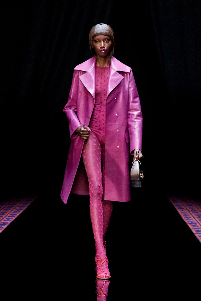 a model wearing a hot pink printed catsuit and trench coat on the Lanvin runway