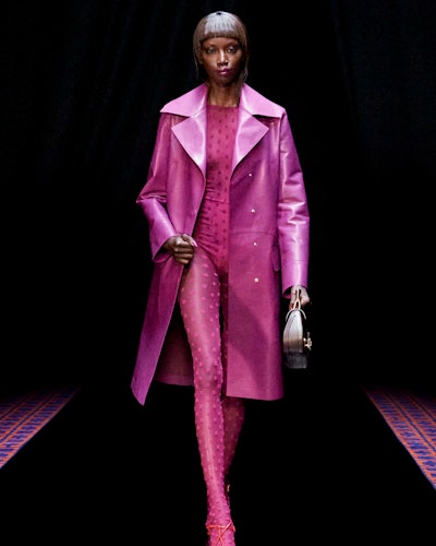a model wearing a hot pink printed catsuit and trench coat on the Lanvin runway