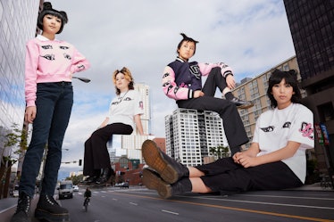 The Linda Lindas wearing tshirts and varsity jackets from their opening ceremony collaboration