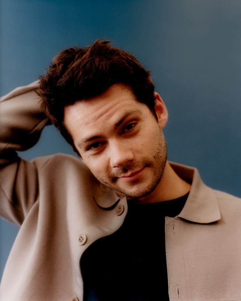 Dylan posing in a black shirt and a light brown jacket