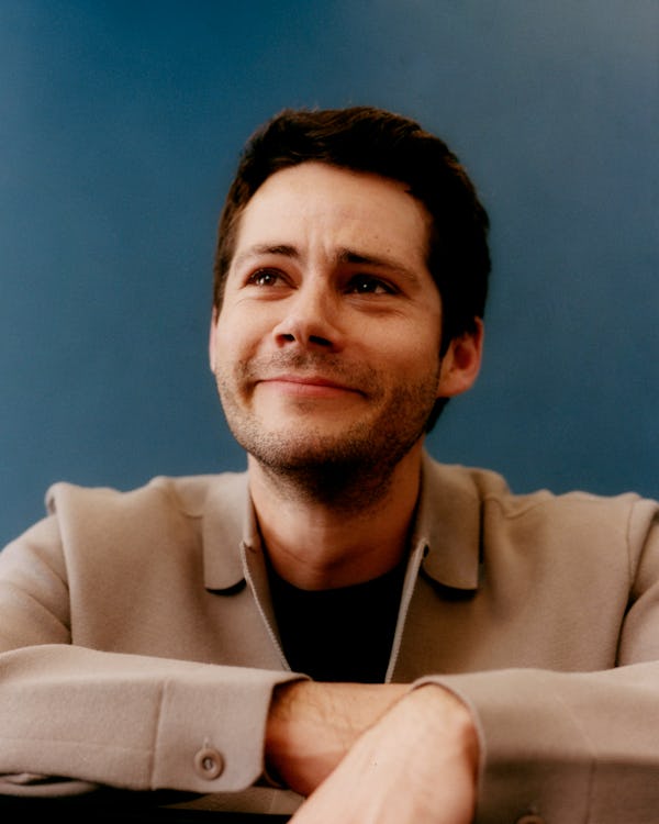 Dylan O’Brien looking upwards in a light brown jacket